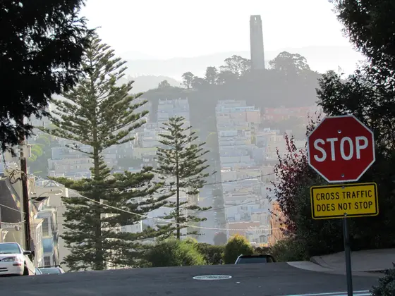 Coit Tower above a San Francisco street, past a stop sign